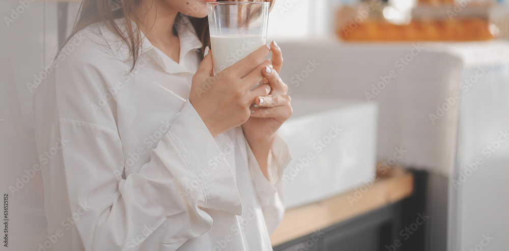 Portrait of a satisfied young asian woman drinking milk from the glass isolated over white background Portrait of a satisfied young asian woman drinking milk from the glass isolated over white background