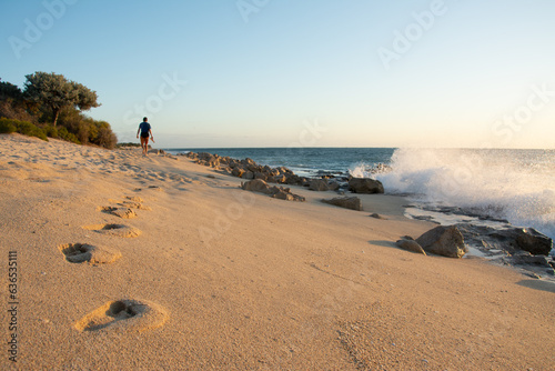 A man walking on sandy beach during the sunset leaving footprints. Anakao Beach, Madagascar.  photo