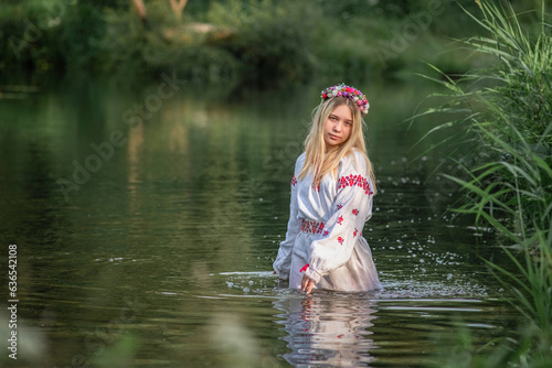 Fototapeta Naklejka Na Ścianę i Meble -  Portrait of a beautiful fair-haired girl in national clothes near a forest river.