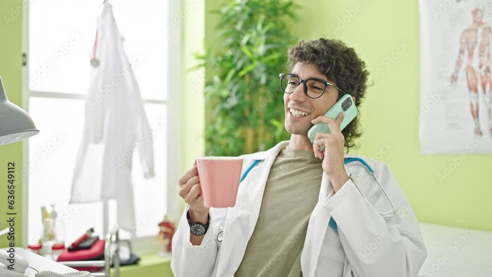 Young hispanic man doctor talking on smartphone drinking coffee at clinic Young hispanic man doctor talking on smartphone drinking coffee at clinic