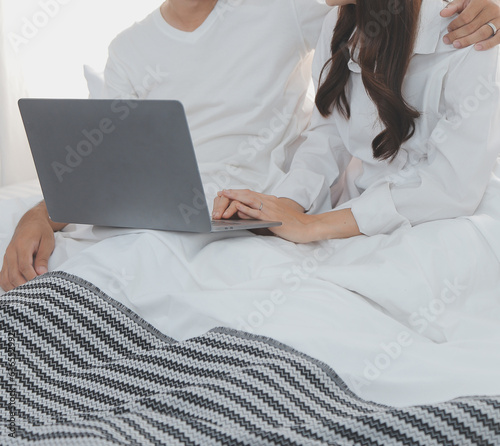 Portrait of young happy couple using laptop at night, using modern technology having fun with glowing screen in dark office or at home, startup business meeting video call distance of young business © ARMMY PICCA