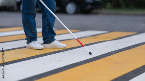 Close-up of the legs of a blind woman crossing the road at a crosswalk with a cane.  © Михаил Решетников