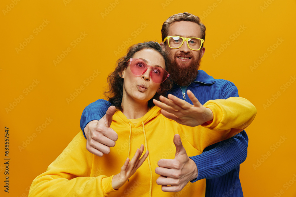 Obraz premium Man and woman couple smiling cheerfully and crooked with glasses, on yellow background, symbols signs and hand gestures, family shoot, newlyweds.