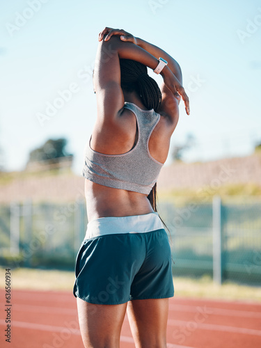 Stretching, sports and exercise with a woman outdoor on a track for running, training or workout. Behind African athlete person at stadium for arm stretch, fitness and muscle warm up or body wellness