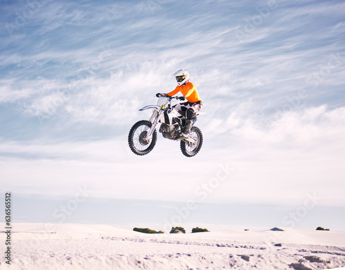 Bike, speed and jump with a man on sand riding a vehicle in the desert for adventure or adrenaline. Motorcycle, training and freedom with an athlete in the sky in nature for power or competition © D Theron/peopleimages.com