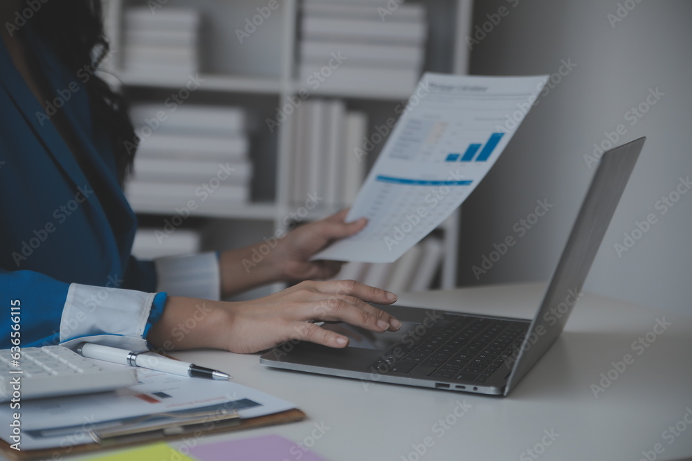 Asian Businesswoman Using laptop computer and working at office with calculator document on desk, doing planning analyzing the financial report, business plan investment, finance analysis concept. Asian Businesswoman Using laptop computer and working at office with calculator document on desk, doing planning analyzing the financial report, business plan investment, finance analysis concept.