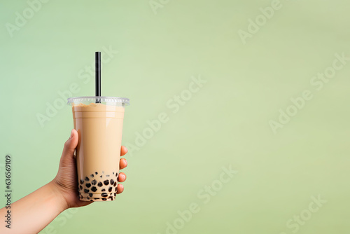 A hand holding takeaway plastic cup of delicious iced bubble milk tea and black pearls with copy space