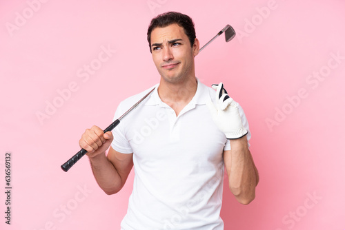 Young golfer player man isolated on pink background with fingers crossing and wishing the best