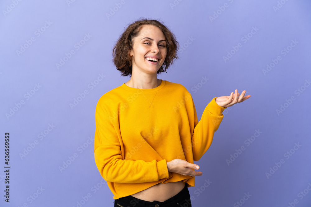 Young English woman isolated on purple background extending hands to the side for inviting to come Young English woman isolated on purple background extending hands to the side for inviting to come