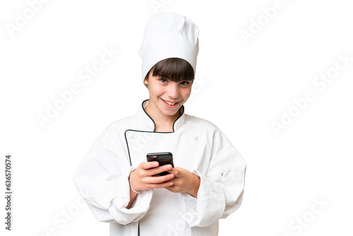 Little caucasian chef girl over isolated background sending a message with the mobile © luismolinero