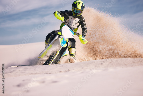 Motorcycle, dust and energy with a sports man riding a vehicle in the desert for adventure or adrenaline. Bike, freedom and training on sand with an athlete outdoor in nature for power or competition