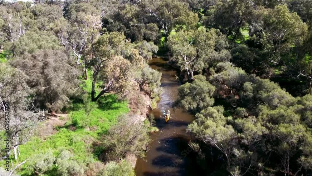 Two man yellow Kayak travelling down stream in narrow river. Aerial tracking