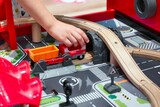 Close-up of a child's arm and hand playing with a toy train set