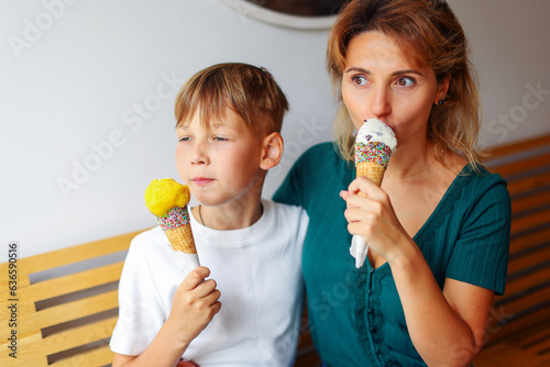 An attractive middle-aged woman with her teenage son sitting in cafe and eating ice cream