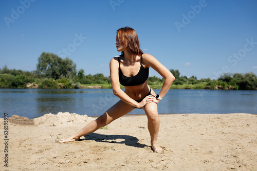 athletic woman doing fitness stretching on the beach in summer
