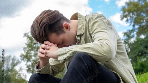 A sad young man sitting in nature