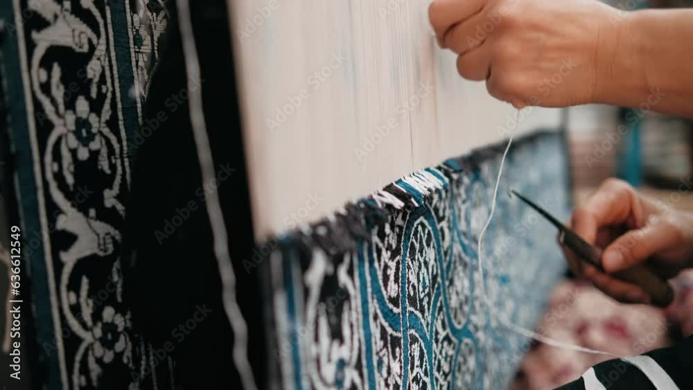 Woman weaves a traditional Arabic carpet of multicolored wool. Weaving and making handmade carpets close-up. Needlework. Handcraft