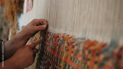Woman weaves a traditional Arabic carpet of multicolored wool. Weaving and making handmade carpets close-up. Needlework. Handcraft
