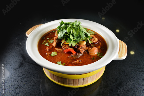 spicy mala laksa curry hot clay pot with seafood prawn, scallop, chicken meat, vegetable, noodle and chilli sambal thick gravy sauce in bowl on black table asian halal food cuisine menu for restaurant photo