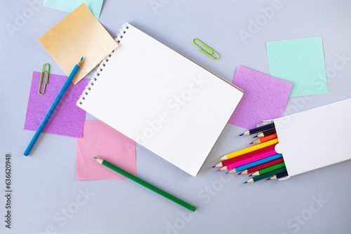 Back to school, colorful sticky notes and multicolored pencils, drawing supplies on gray blue background with copy space, top view, flatly