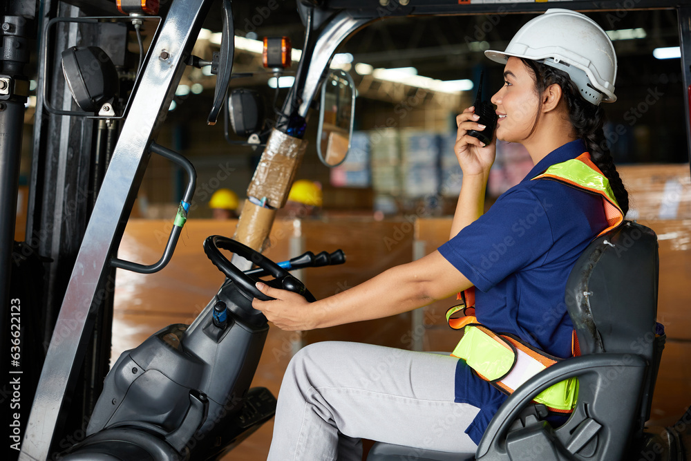 Indian worker driving a forklift and using walkie talkie in warehouse storage Indian worker driving a forklift and using walkie talkie in warehouse storage
