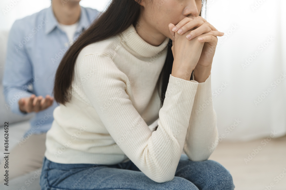 Family problems, Asian women cover her face and sit separately from husband feel disappointed after quarrels at home.