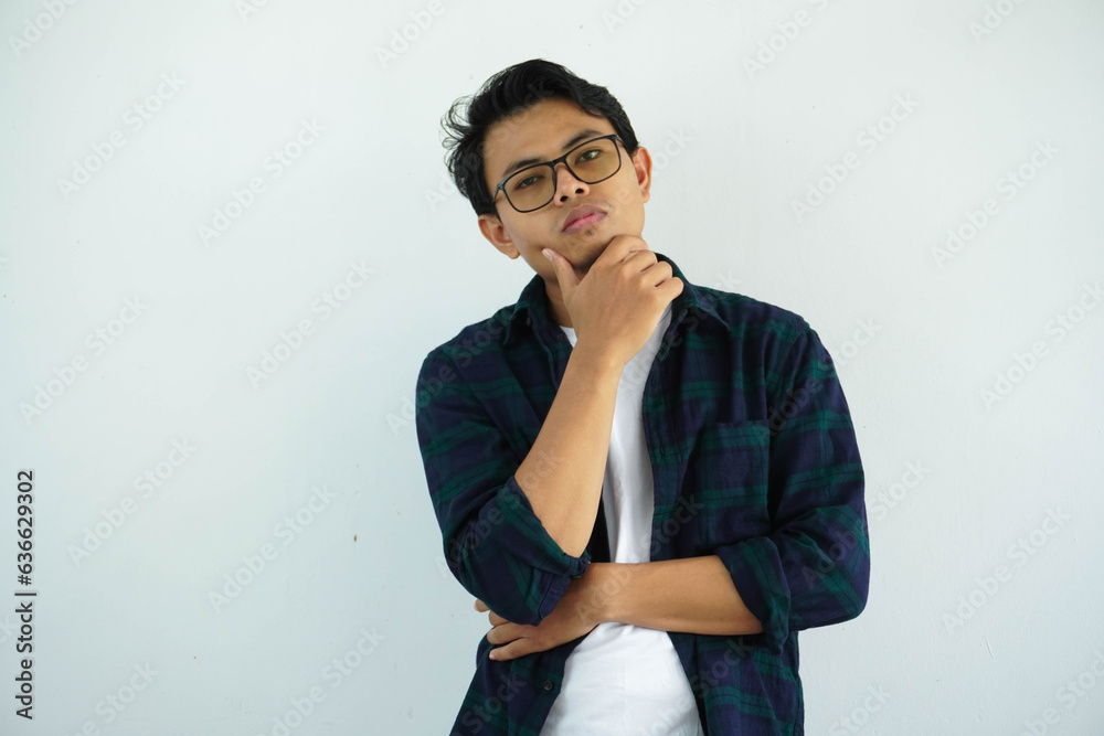 young asian man showing gloomy expression with hand holding chin isolated on white background young asian man showing gloomy expression with hand holding chin isolated on white background