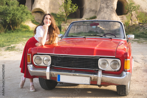 beautiful happy girl in a skirt posing near a retro car in the mountains of cappadocia