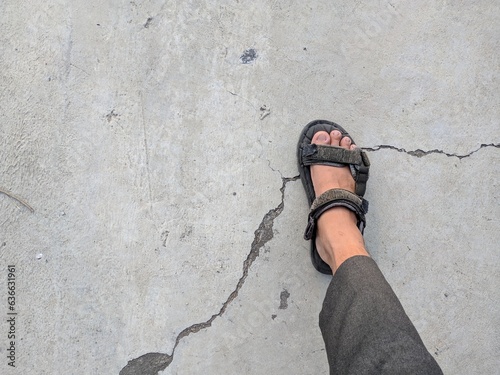 Young man wears black vintage slippers and steps forward on the cement floor