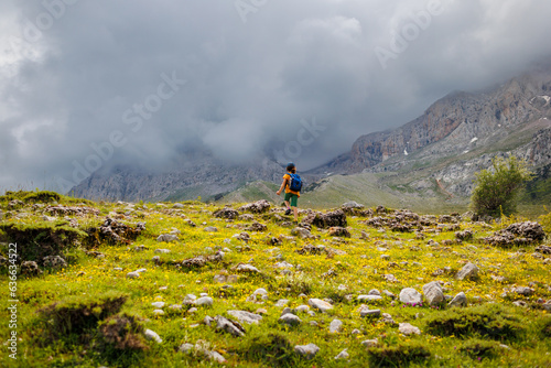traveler child with backpack relaxing outdoors with rocky mountains in the background.