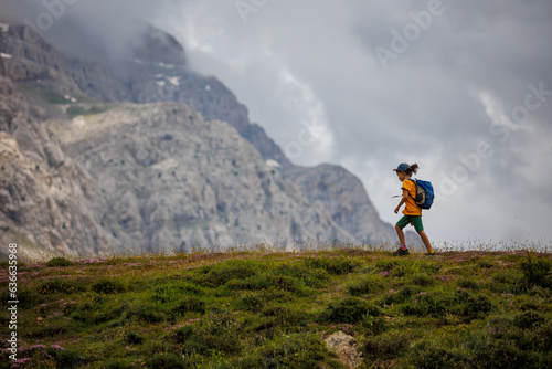 boy with a backpack on a hike against the backdrop of the mountains. child traveler with backpack, hiking, travel, mountains in the background, kids summer vacation.