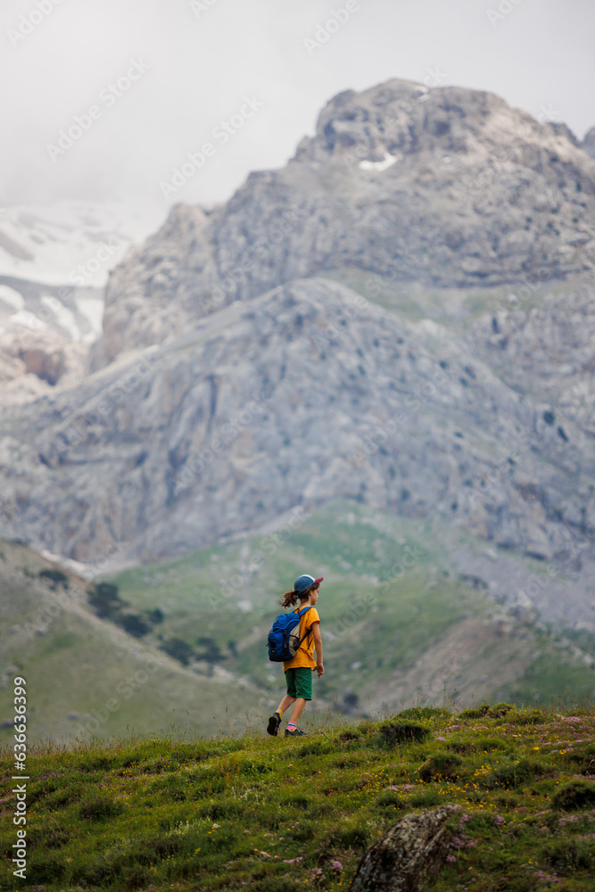 boy with a backpack on a hike against the backdrop of the mountains. child traveler with backpack, hiking, travel, mountains in the background, kids summer vacation.