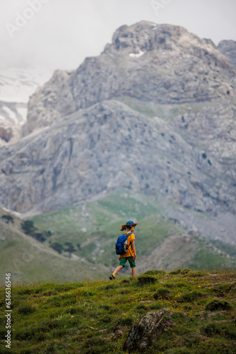 boy goes with a backpack on the background of the mountains. child traveler with backpack, travel, lifestyle concept