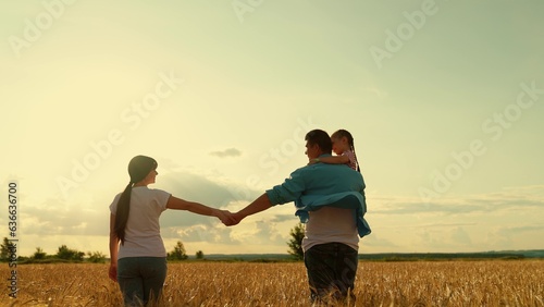 Happy mother, father, little daughter enjoying nature together, outdoors. Happy family of farmers with child, are walking on wheat field. Slow motion. Mom, dad, child walk hand in hand. People travel