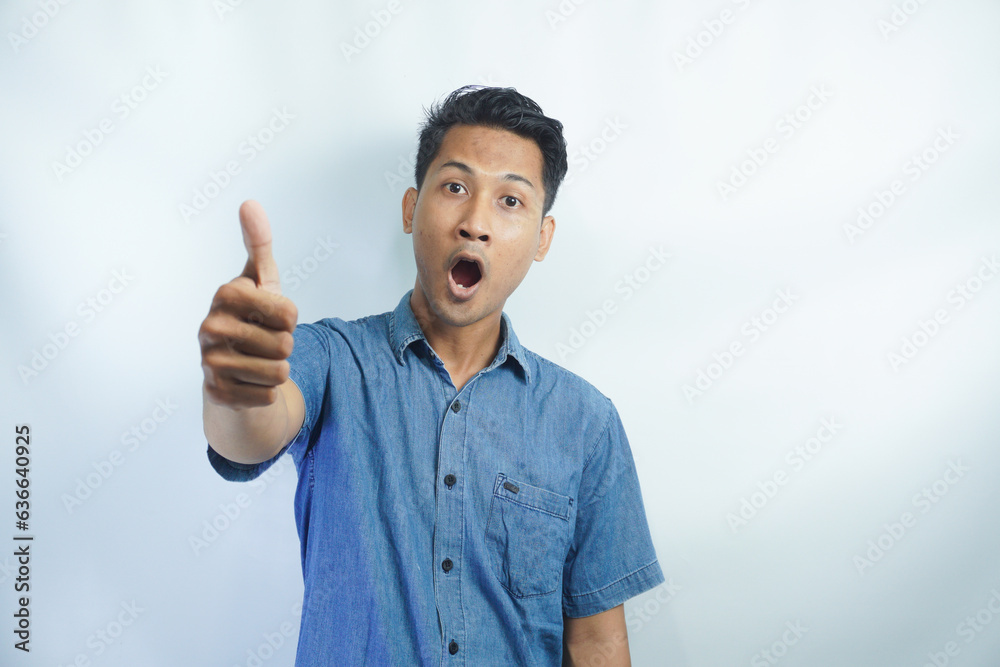 Young handsome Asian man wearing a blue shirt over isolated white background with thumbs up because something good has happened Young handsome Asian man wearing a blue shirt over isolated white background with thumbs up because something good has happened