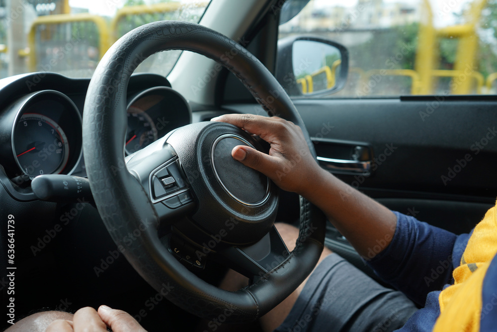 man holding steering wheel of car, black man driving car 