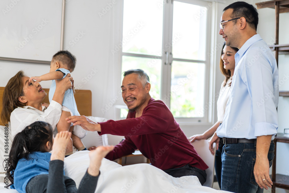 Obraz premium Portrait of happy love asian grandfather with grandmother playing with asian baby and little cute girl on bed.Big family love with their laughing grandparents smiling together.Family and togetherness