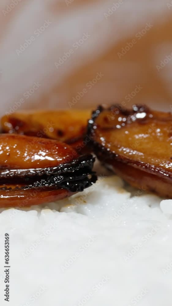 Vertical video. The woman spreads the cooked mussel meat evenly on the layer of rice in a close-up shot. Vertical video. The woman spreads the cooked mussel meat evenly on the layer of rice in a close-up shot.