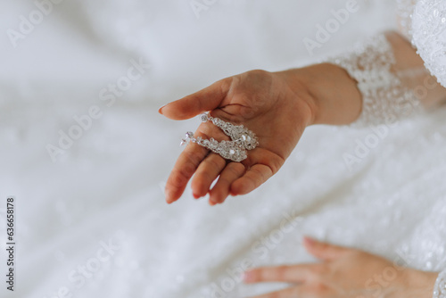 The bride holds in her hands and shows her earrings with precious stones, close-up. Morning of the bride. The wedding day.