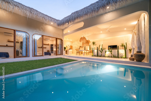 Tropical villa view with garden, swimming pool and open living room at sunset