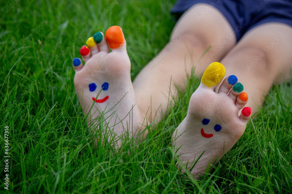 Fototapeta premium a boy on the grass with a painted smile on his feet.. Selective focus