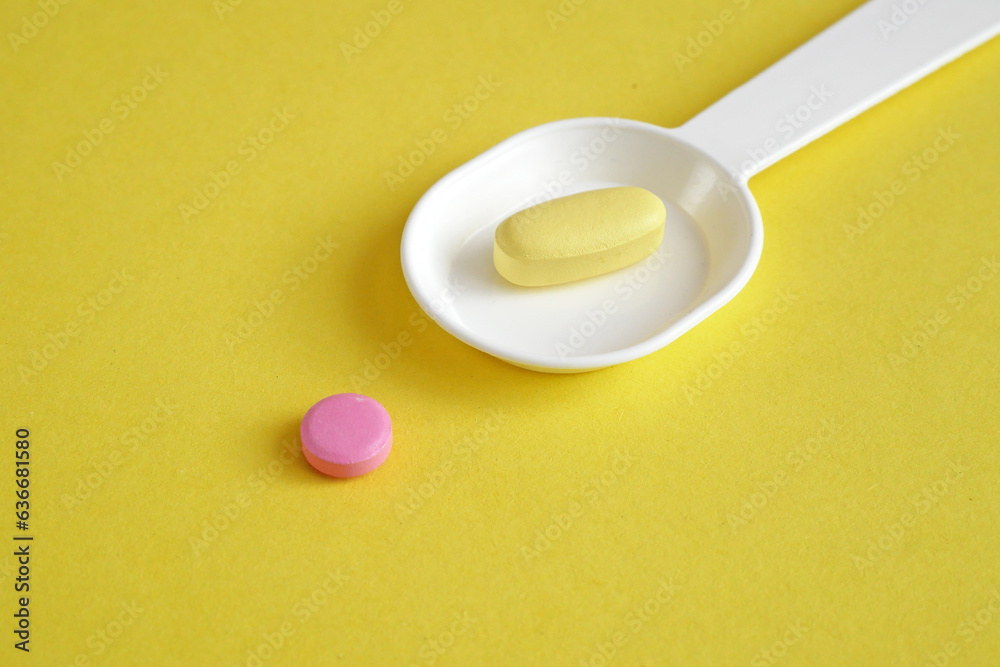 spoon with pills and tablets on yellow background. checking ingredients and effectiveness of medicine spoon with pills and tablets on yellow background. checking ingredients and effectiveness of medicine