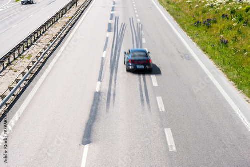 Car driving fast down a highway with log tire skid marks. © Trygve