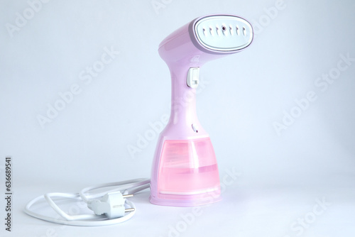 Pink laundry steamer isolated on a grey background. Manual steaming of laundry