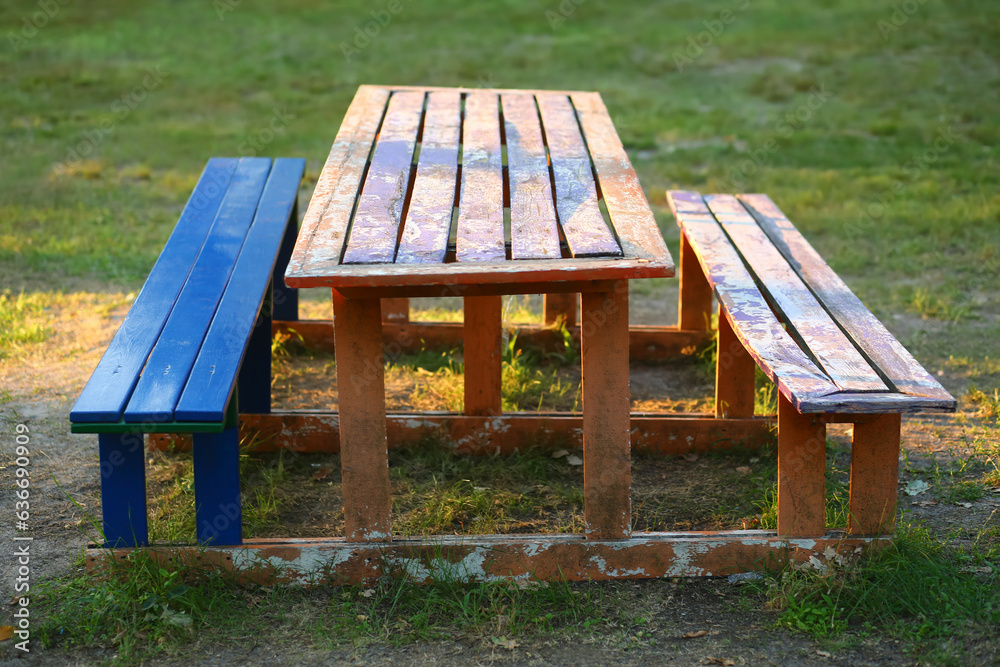 Old wooden benches and a table for a picnic in the sunlit summer park Old wooden benches and a table for a picnic in the sunlit summer park