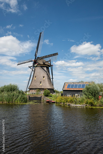 iconic smock ground sailer windmill in Kinderdijk Netherlands. Landmark buildings originally made to pump water out of low land polder to preserve land reclaimed from the sea. Solar sun panels on shed
