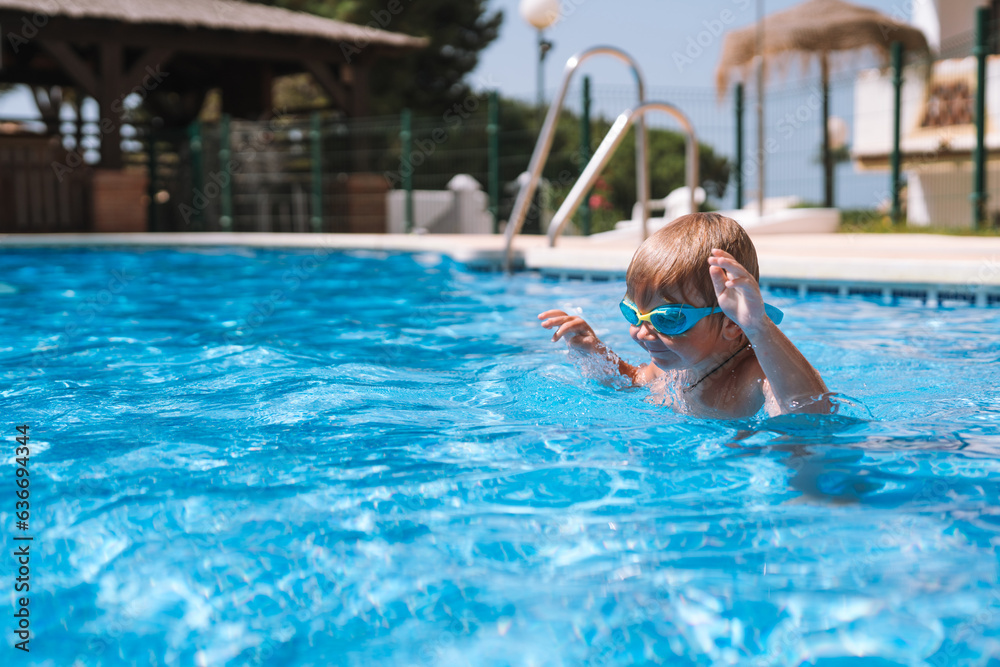 little boy swims in the pool in swimming goggles