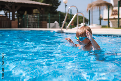 little boy swims in the pool in swimming goggles © sutulastock