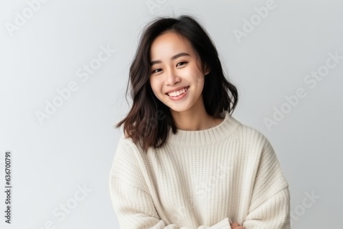 Medium shot portrait of a Chinese woman in her 20s in a white background wearing a cozy sweater photo