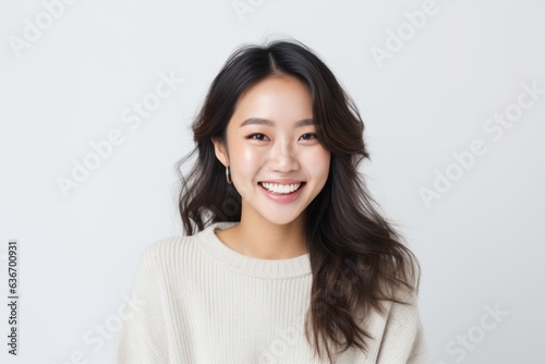 Lifestyle portrait of a Chinese woman in her 20s in a white background wearing a cozy sweater